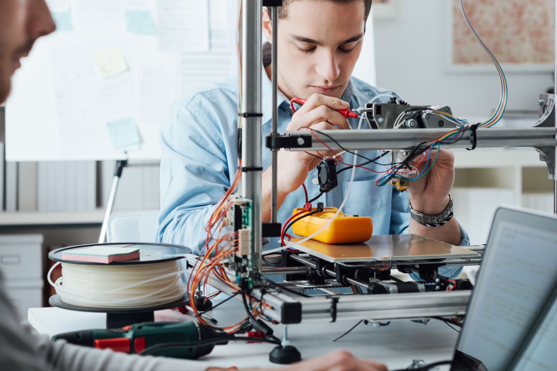 Engineer testing 3D printer hardware with multimeter